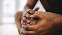 Man clutches knee in pain.
